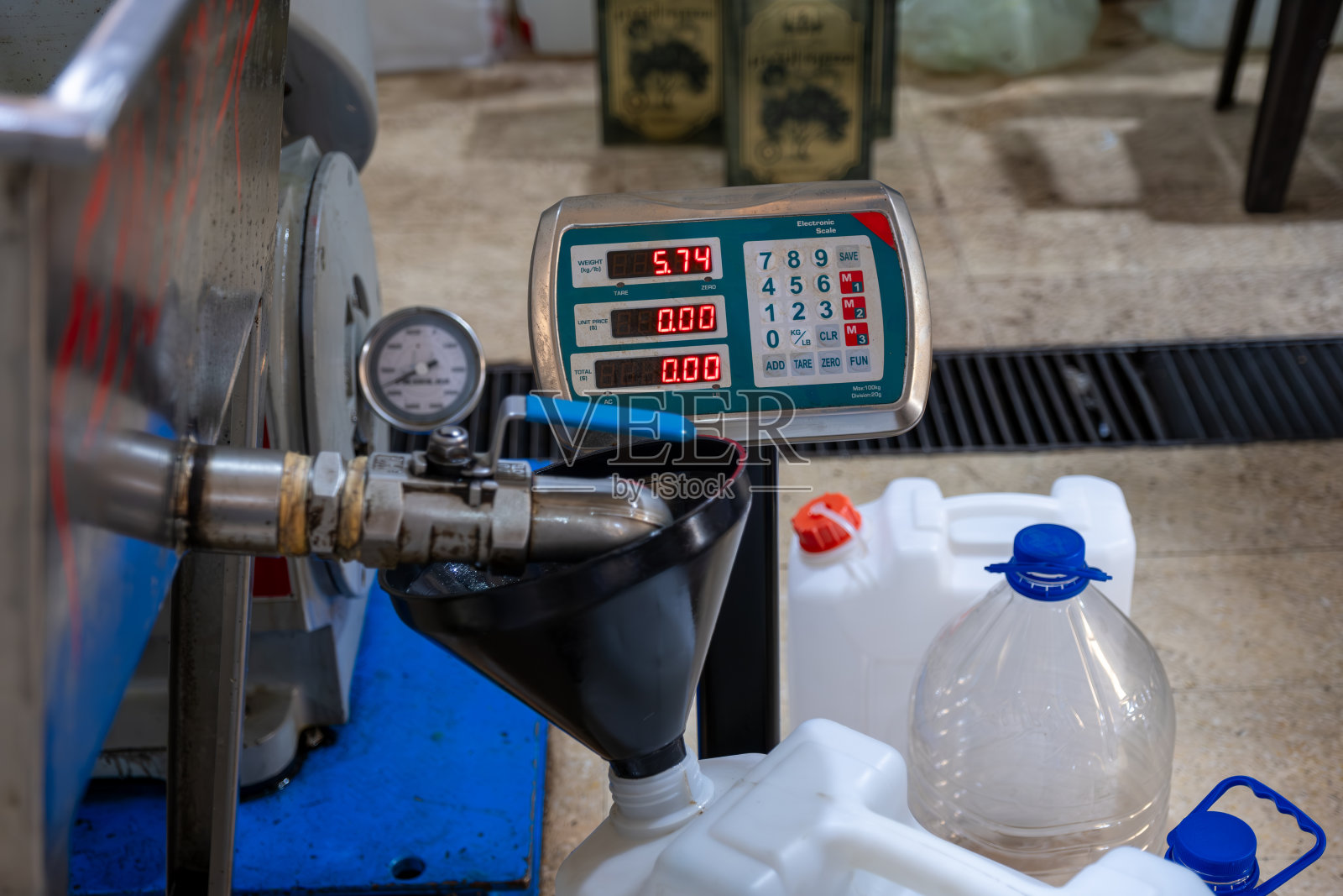 在压榨厂使用漏斗和秤灌装新鲜橄榄油照片摄影图片