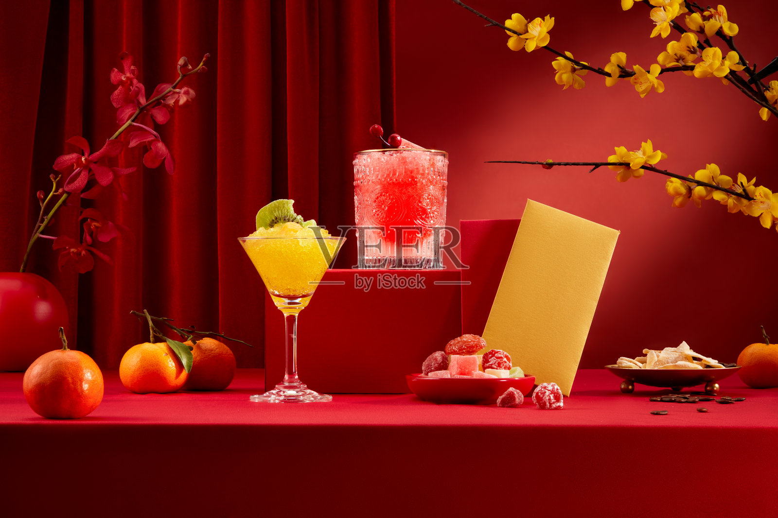 派对桌上有五颜六色的鸡尾酒、果酱、压岁钱信封、橘子、黄杏花等。春节正面广告位。照片摄影图片