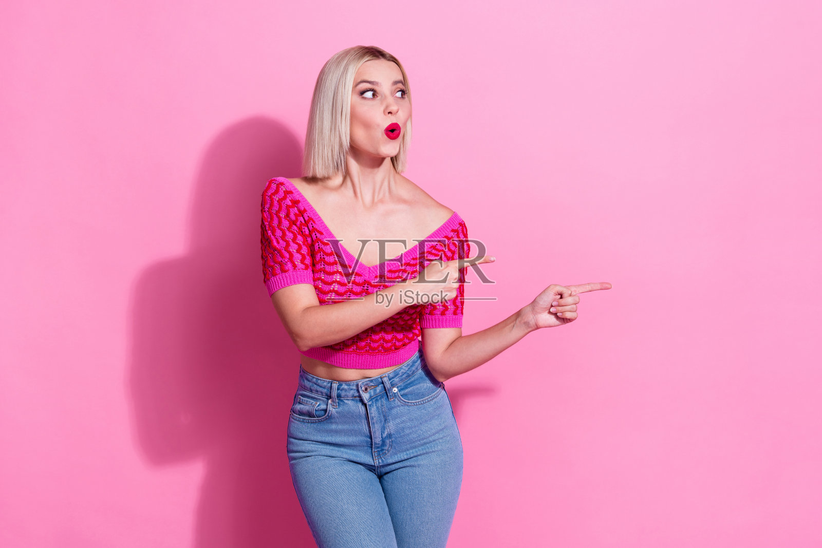 照片中激动的印象华丽的女人穿着针织品的衣服，看起来直接在粉红色的背景上孤立的折扣空间照片摄影图片