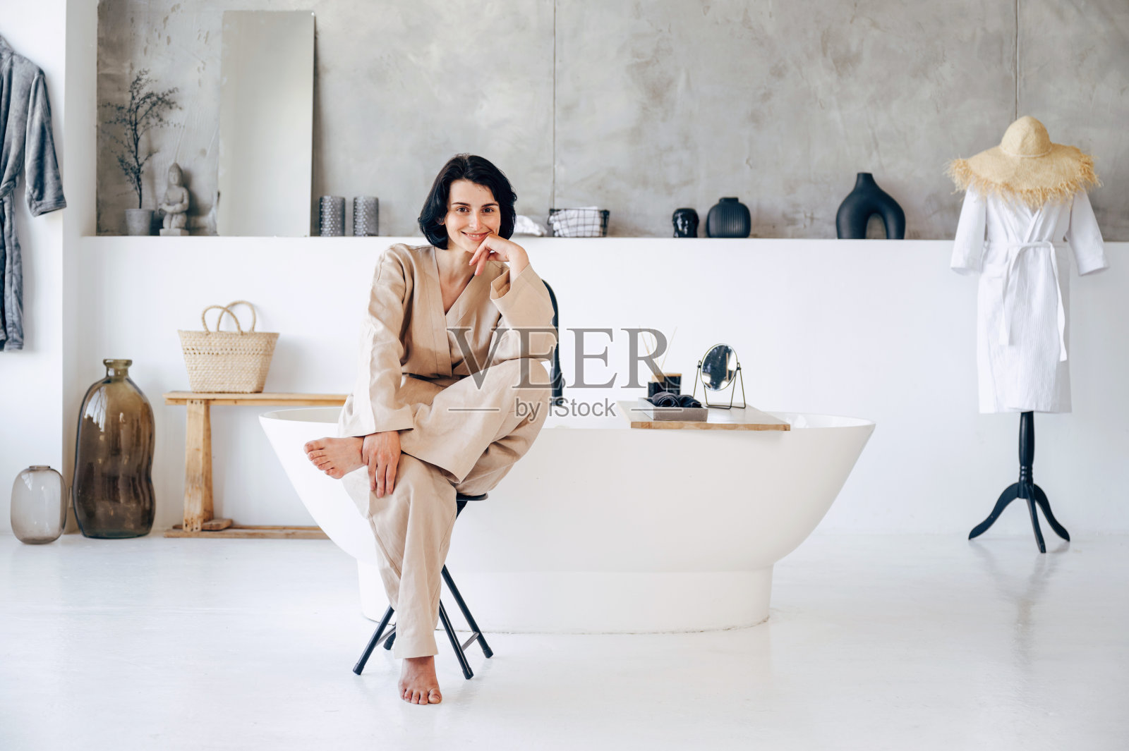 穿着便服的女人坐在椅子上，靠着独立的浴缸照片摄影图片