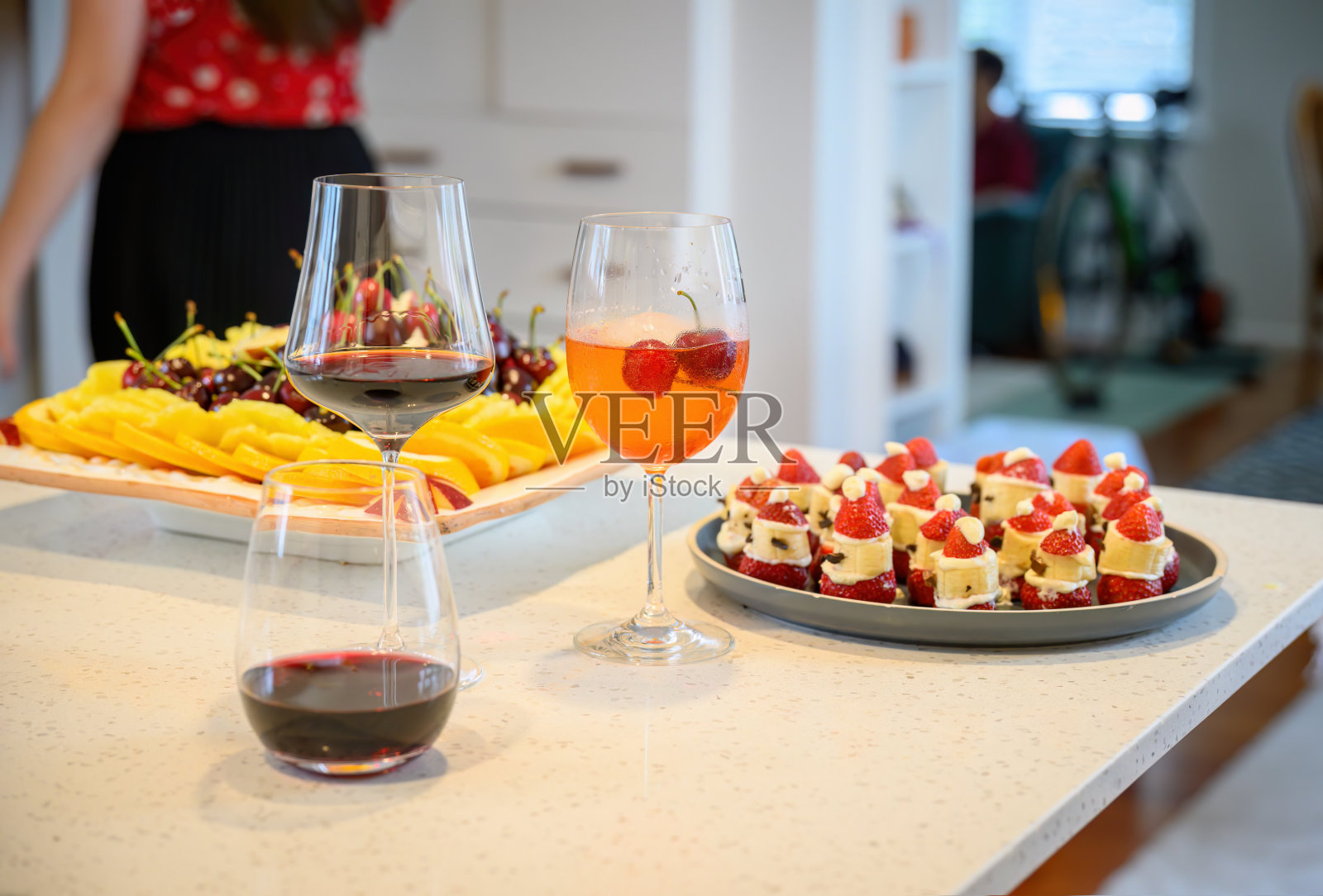 饮料和水果拼盘放在厨房的工作台上。厨房里注意力不集中的人。家庭烹饪和圣诞娱乐。照片摄影图片