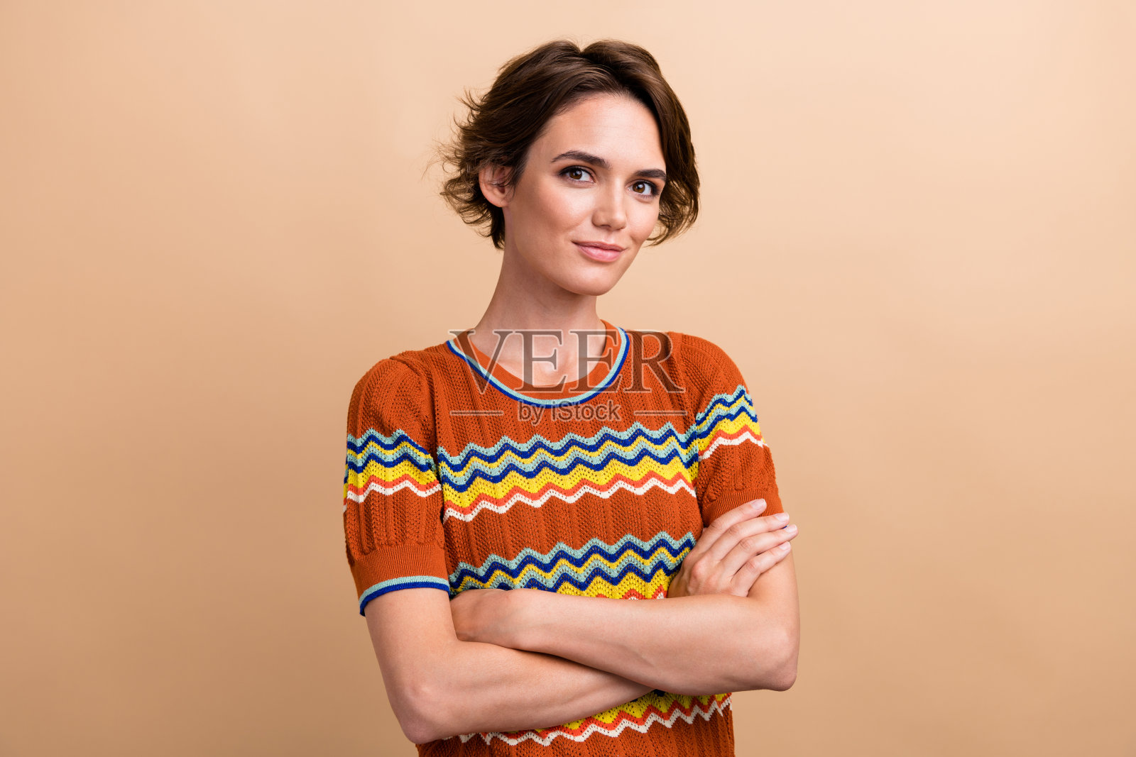 照片肖像可爱的年轻女士交叉双手自信的销售穿着时尚的橙色印花服装孤立的米色背景照片摄影图片