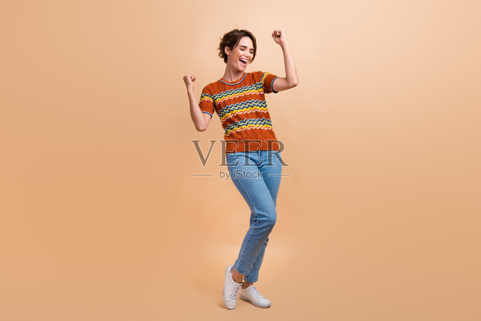 喜出望外的女孩举起拳头，成就成就的全尺寸照片孤立在米色背景上照片摄影图片