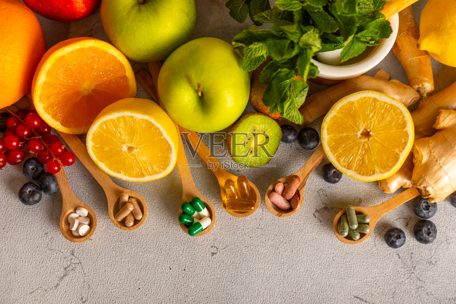 维生素和补品。多种维生素片在木勺纹理背景。多吃新鲜健康的水果。食品补充剂。平的。文本空间。本空间照片摄影图片