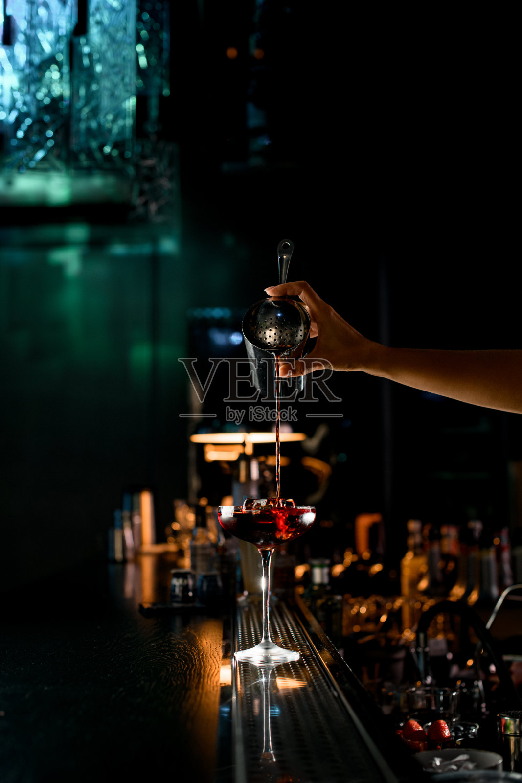 前视图的水晶鸡尾酒杯与冰块，其中填满液体的女人的手照片摄影图片