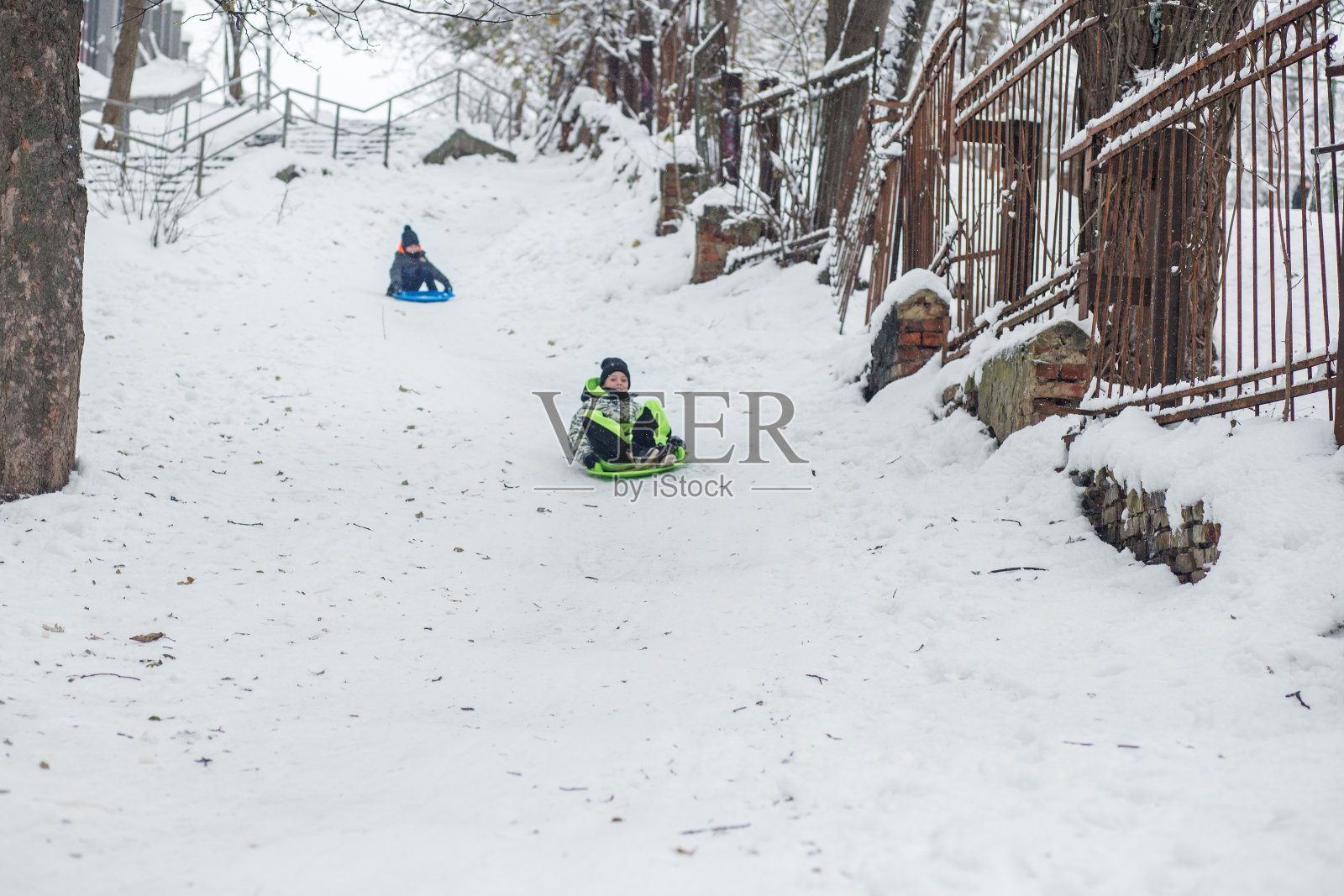 小女孩骑在雪板上。户外玩耍。寒冷的温度。冬天照片摄影图片