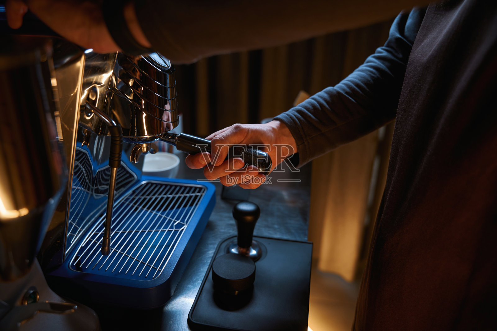 咖啡师手握咖啡机，制作新鲜芳香的咖啡照片摄影图片