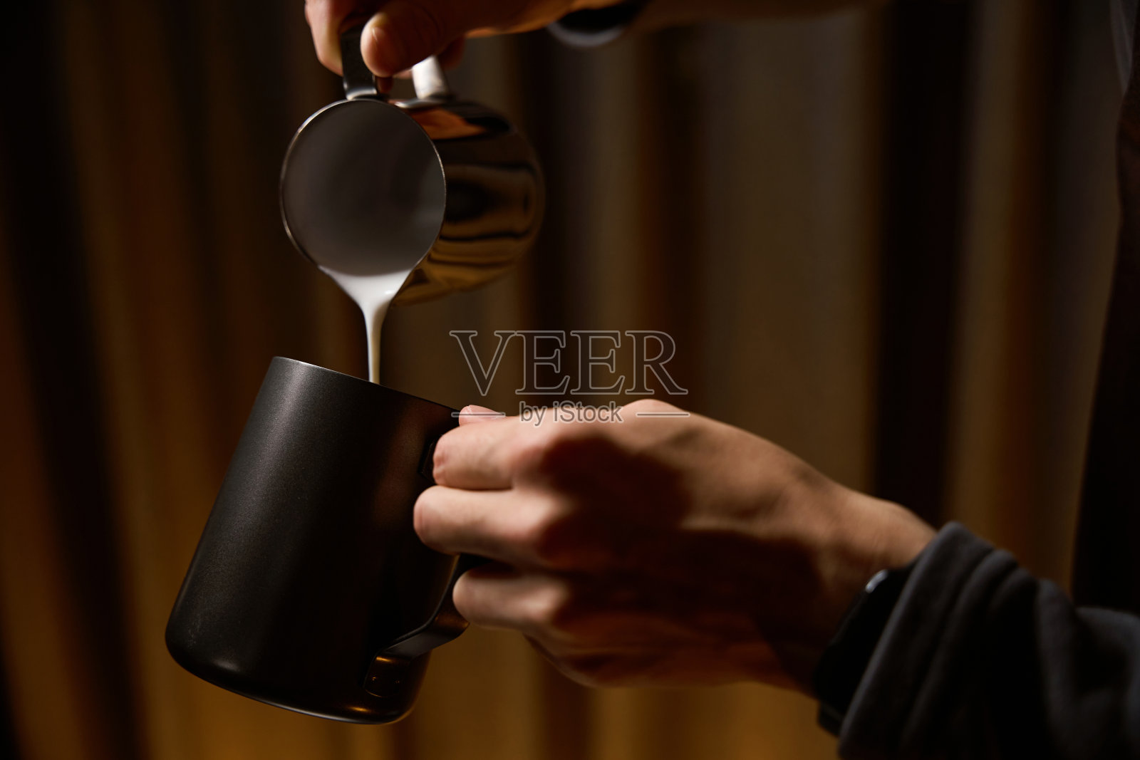 咖啡师用手从煮咖啡的水罐里倒牛奶照片摄影图片