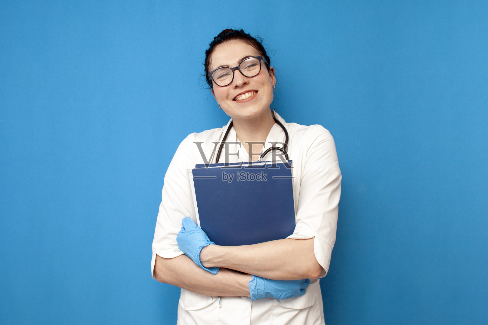 穿着医服的女博士生在一个蓝色的孤立背景上拿着文件和文件，一个实习护士照片摄影图片