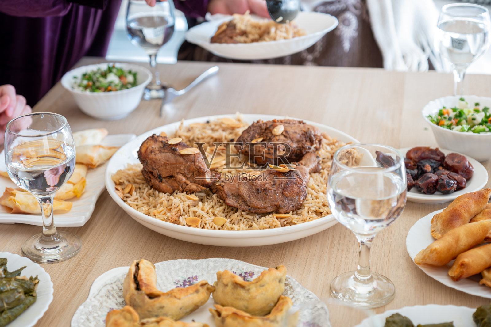 阿拉伯家庭在木桌上共进晚餐，有父亲、母亲、祖父、祖母和儿子照片摄影图片