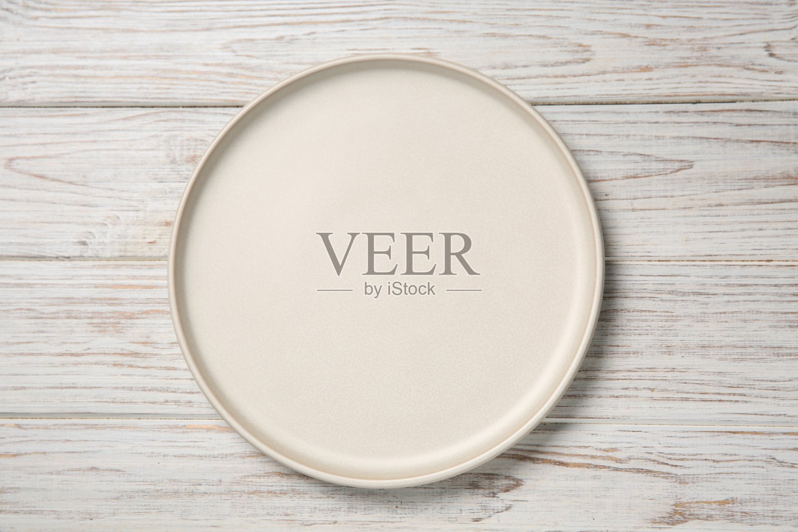 一个白色陶瓷盘子放在轻木桌上，俯视图照片摄影图片