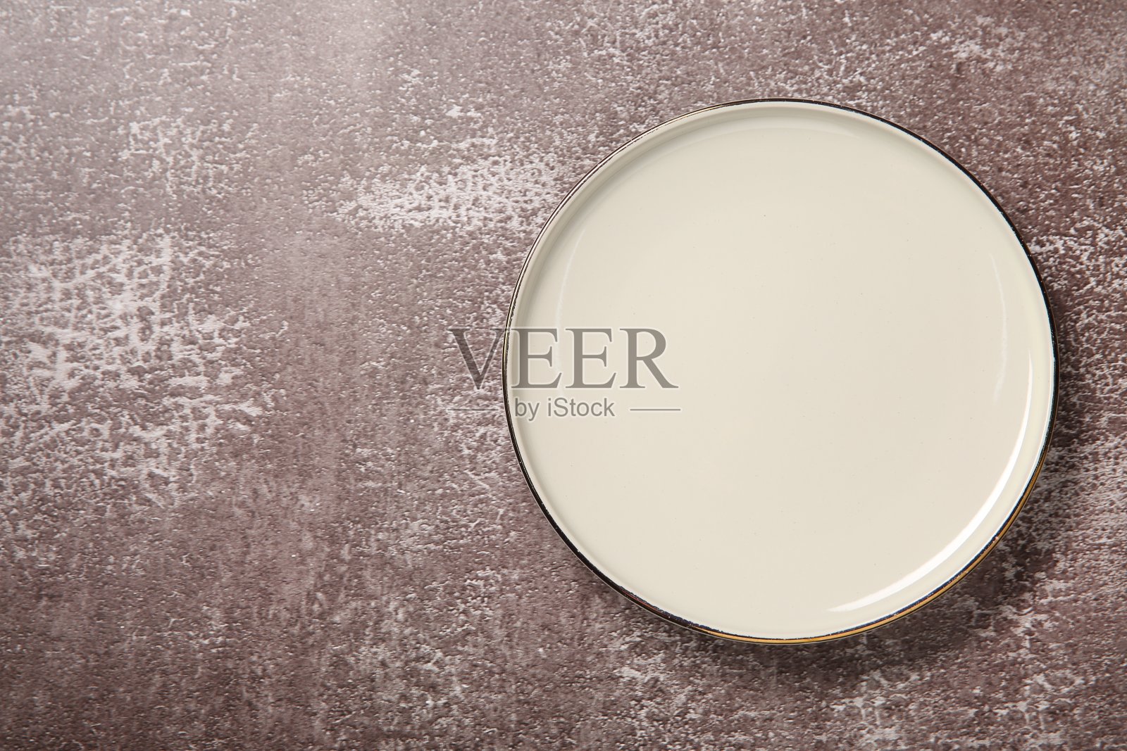 一个白色陶瓷盘子在纹理的桌子上，俯视图。文本空间照片摄影图片