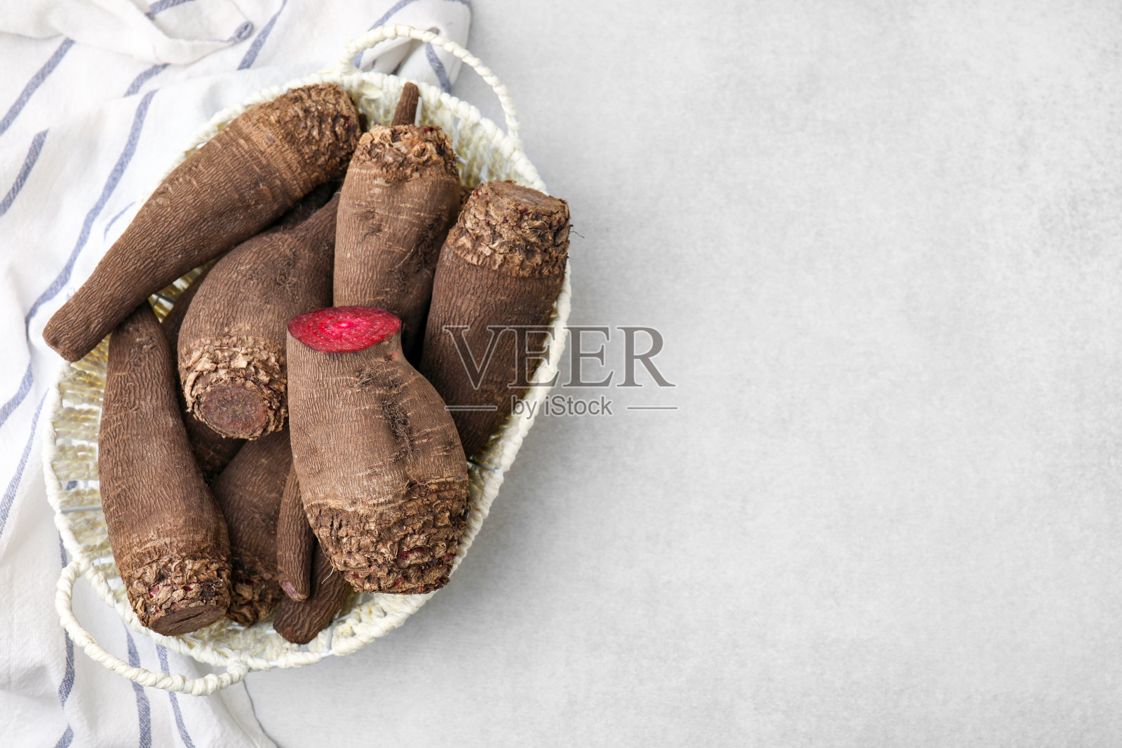 在浅灰色的桌子上，整个和切好的红甜菜放在篮子里，俯视图。文本空间照片摄影图片