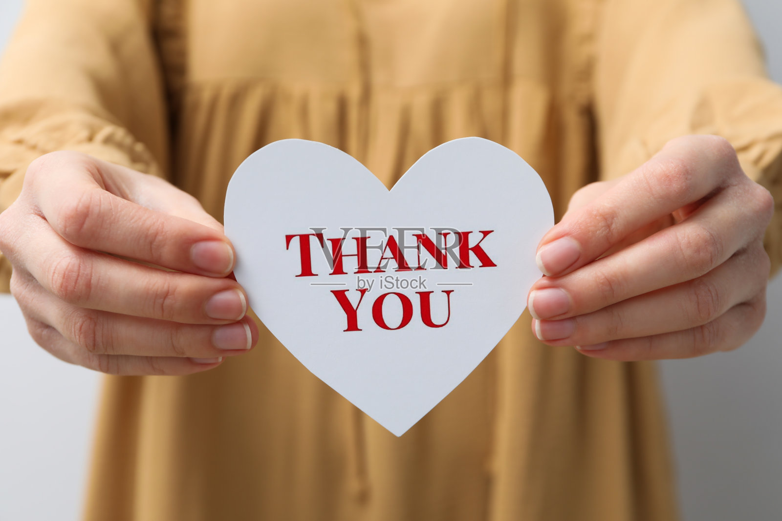 在纸上题词“谢谢你”，用手捧着一颗心照片摄影图片