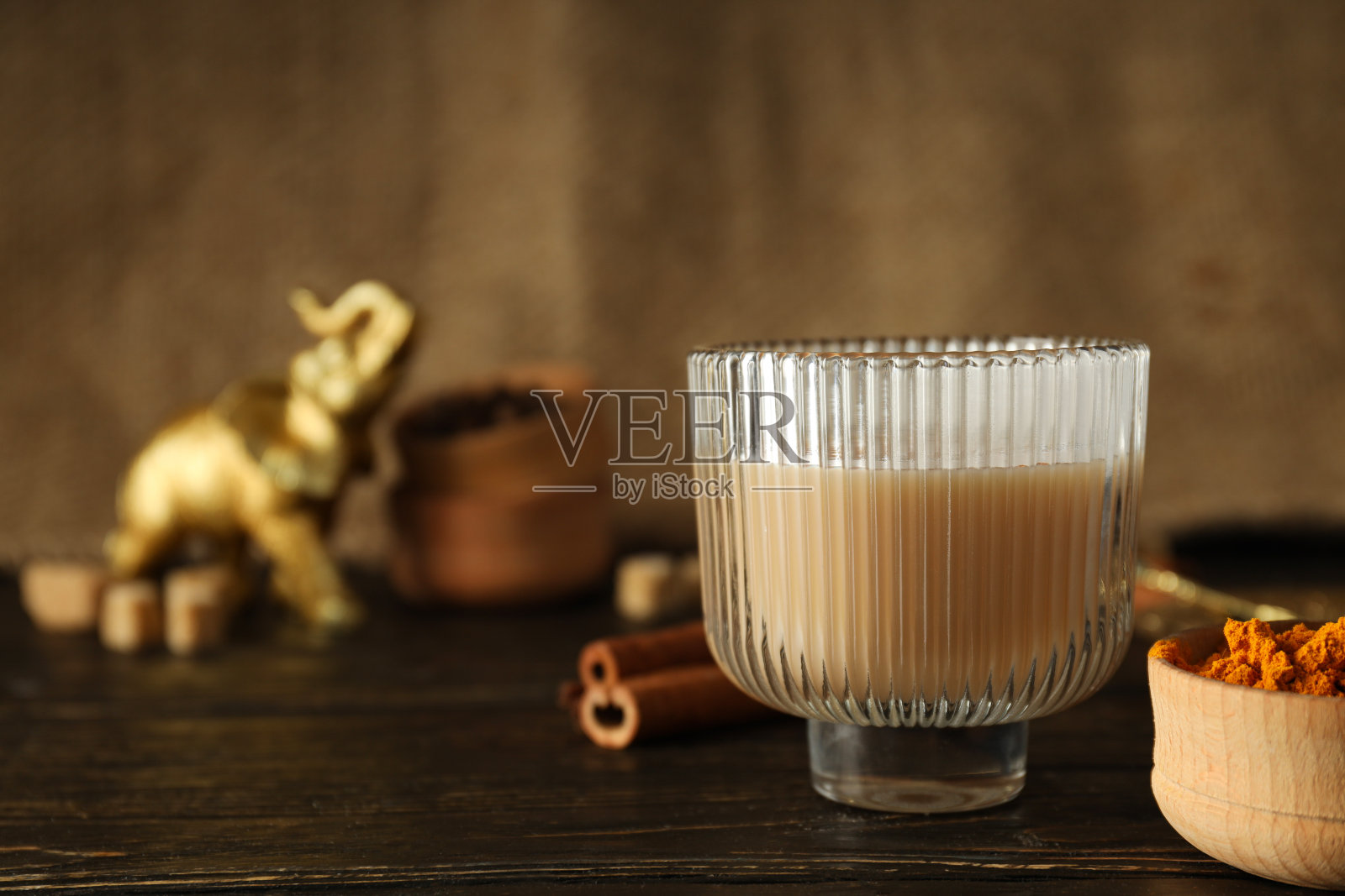 木背景上的玻璃杯里装着马萨拉茶，碗里装着香料照片摄影图片