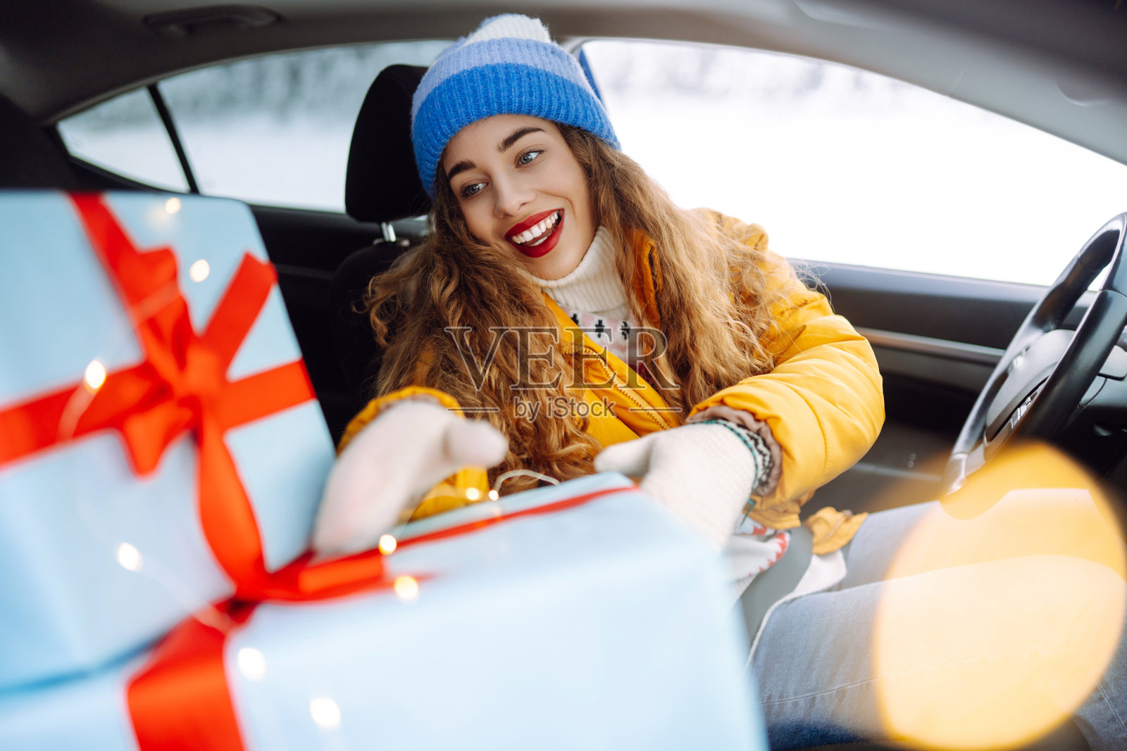 一个涂着鲜艳口红的快乐女人的画像，车里载着圣诞礼物。照片摄影图片