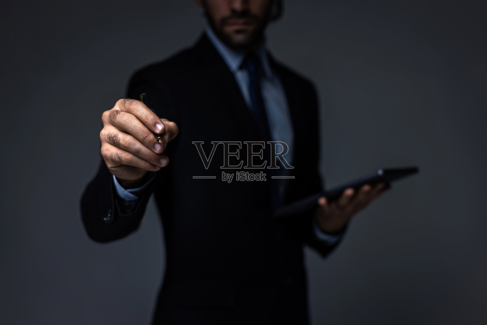 商人用虚拟屏幕手写东西。商人在虚拟屏幕背景上拿着笔。有人在空中写东西照片摄影图片