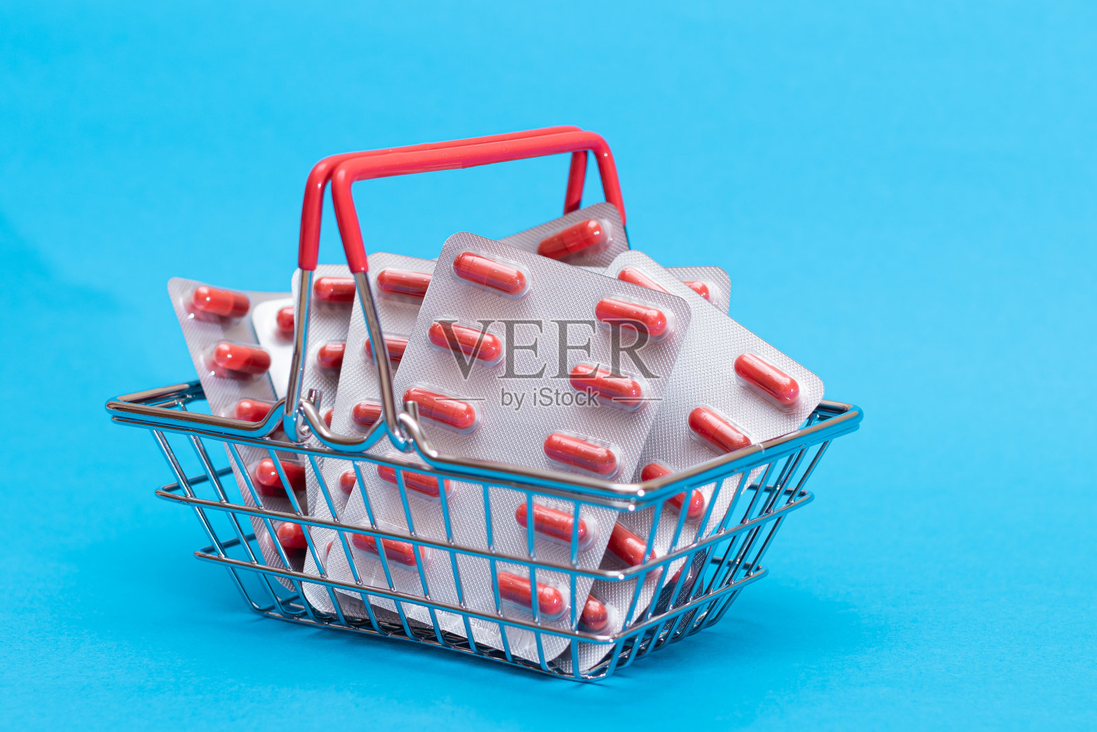 蓝色背景的购物篮里的药丸和胶囊照片摄影图片