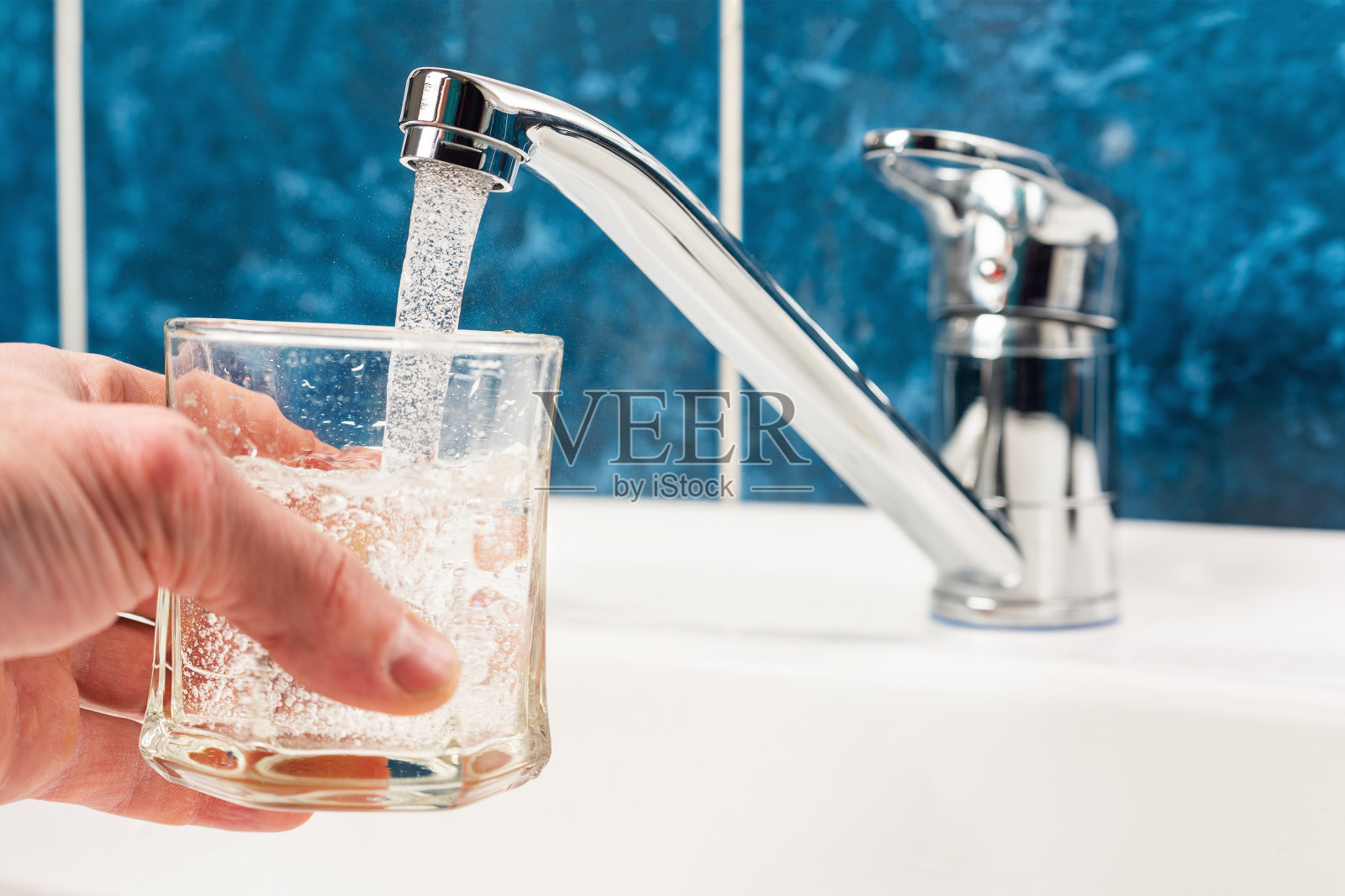 手里拿着一杯从水龙头里倒出来的水照片摄影图片