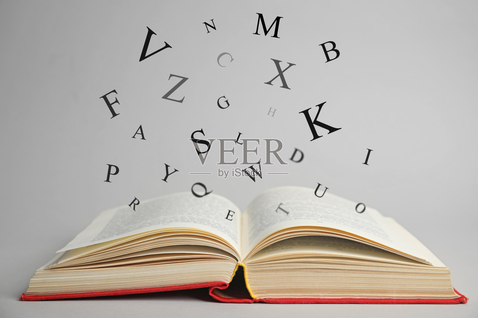打开一本书，在浅色背景下，字母从书里飞出来照片摄影图片
