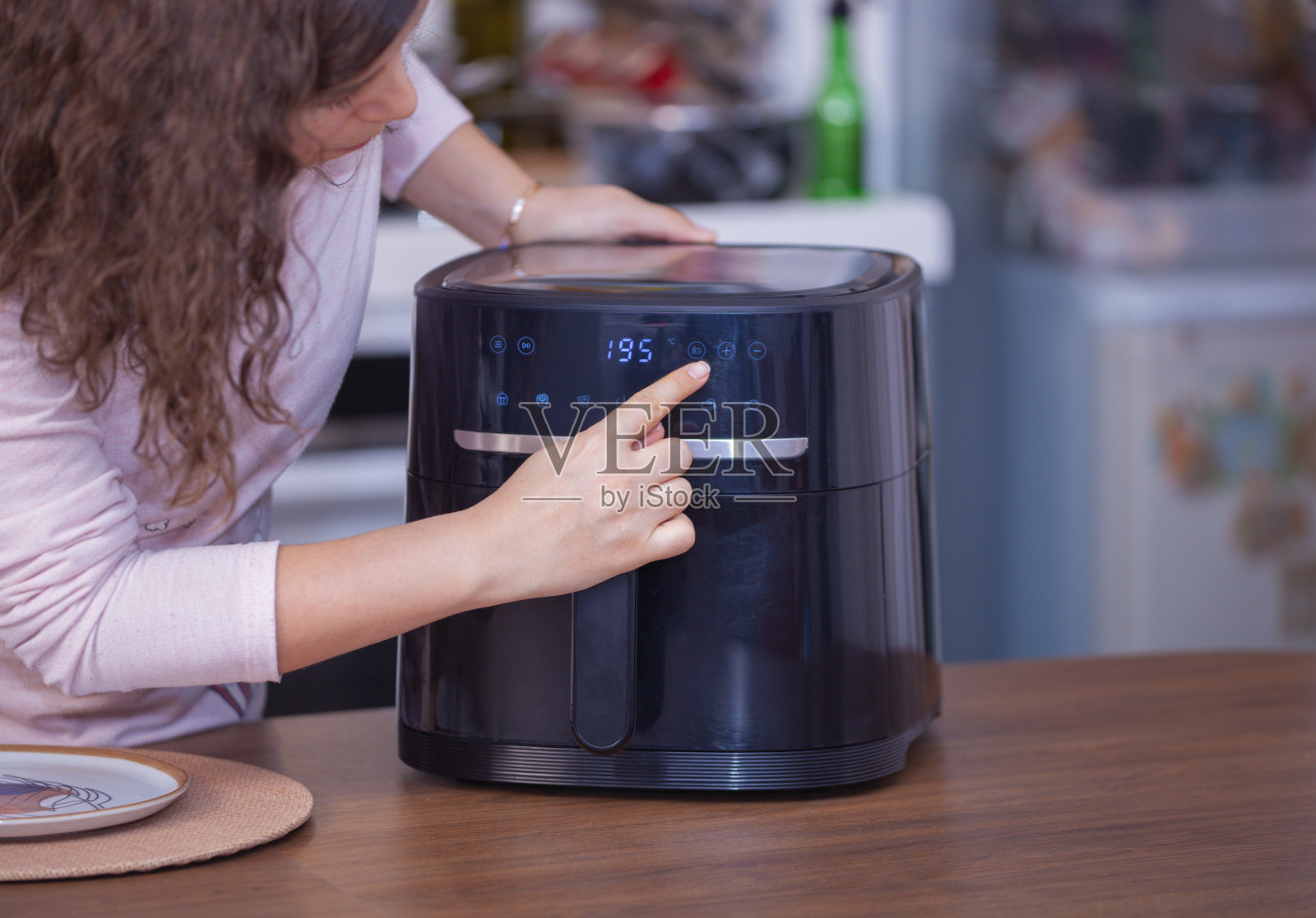 妇女在厨房用空气炸锅做饭。照片摄影图片