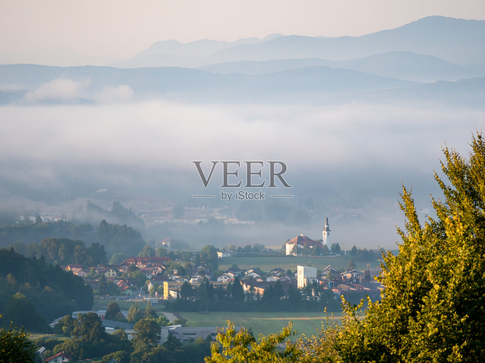 清晨的薄雾在群山背景下的丘陵乡村上空升起照片摄影图片