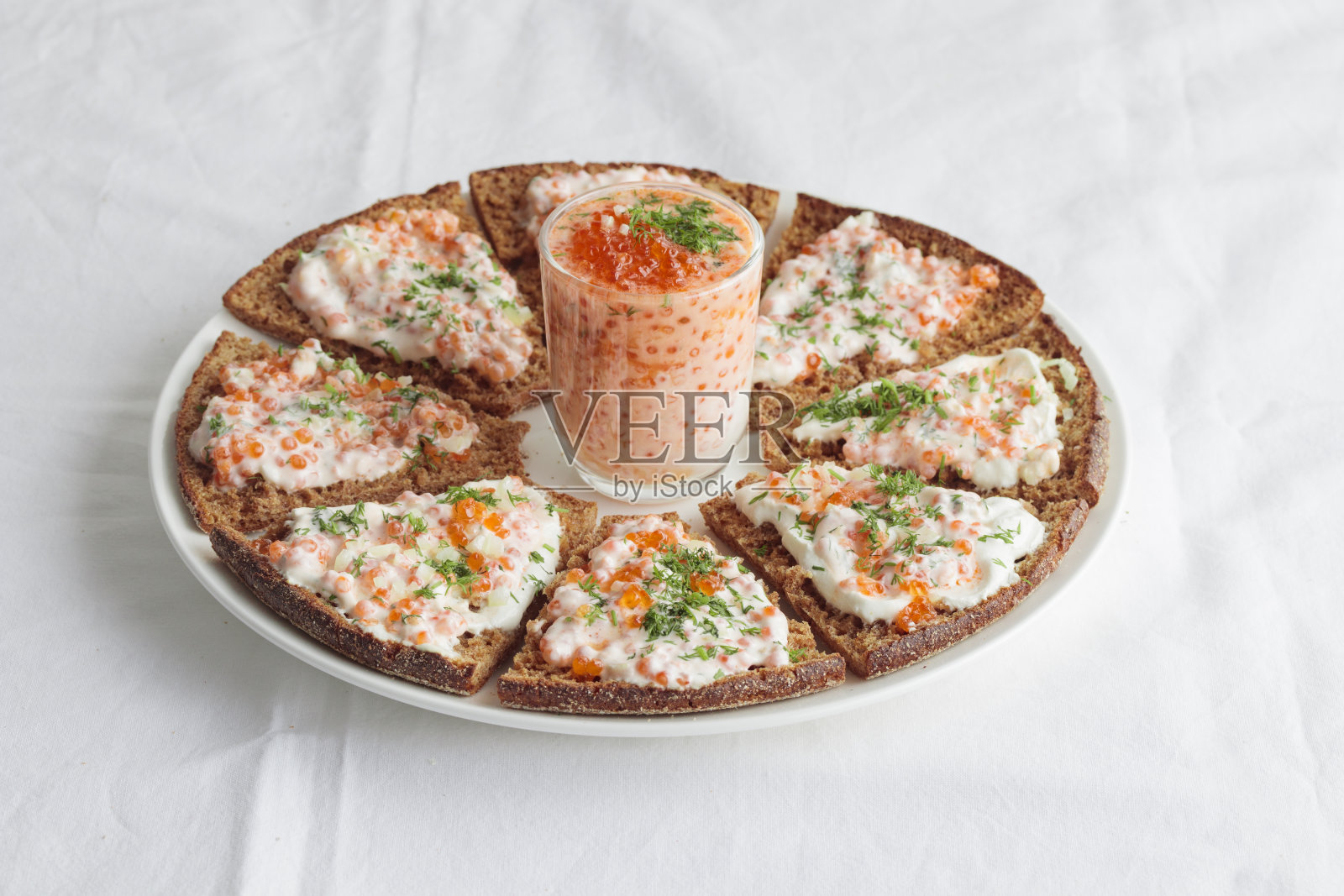 白色餐桌上的开胃菜有红鱼子酱、酸奶油、莳萝、洋葱和黑麦面包——这是芬兰极简风格的节日美食食谱照片摄影图片