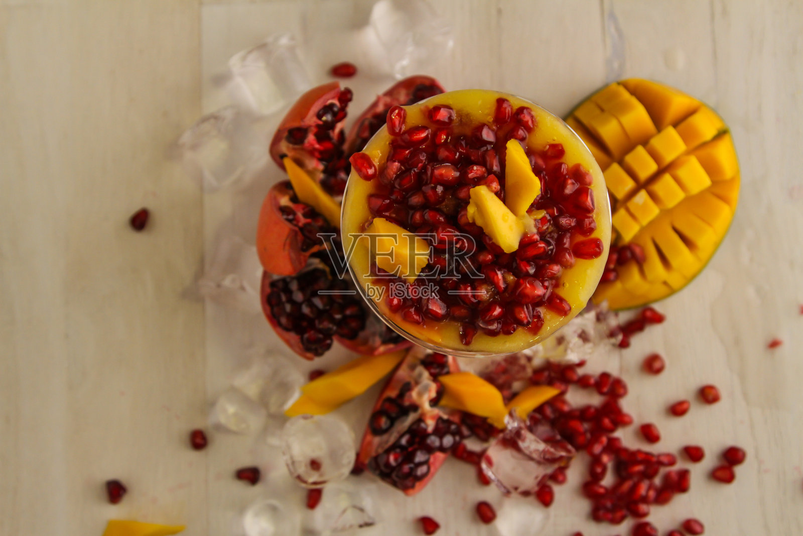 芒果汁和石榴籽服务于一次性玻璃隔离在桌面上的健康饮料的看法照片摄影图片