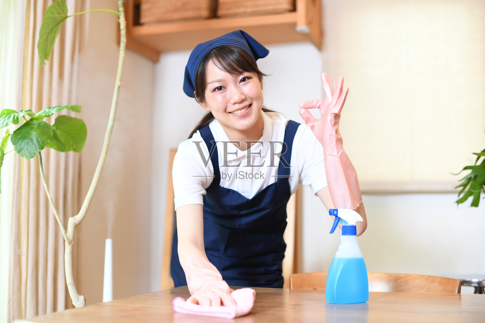 亚洲女管家在打扫客厅时给出OK的手势照片摄影图片