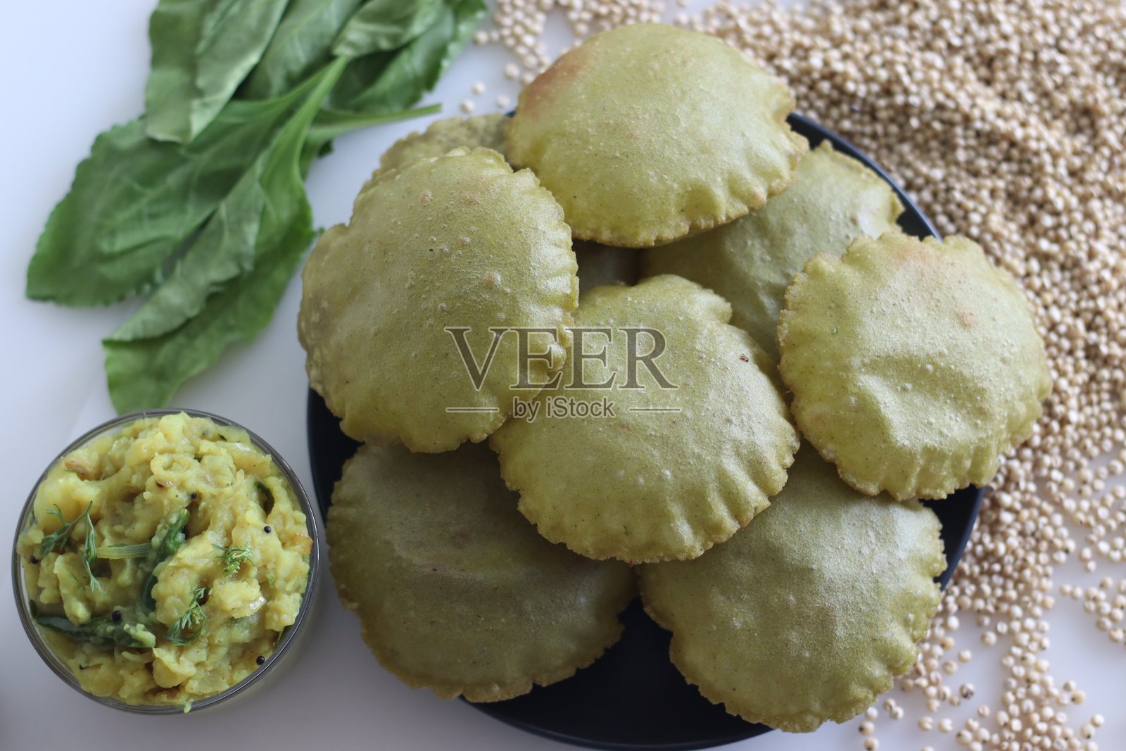 乔瓦帕拉克普里或高粱菠菜炸扁面包。用高粱小米粉和菠菜泥做成的炸面包。配上五香土豆泥肉汁。照片摄影图片