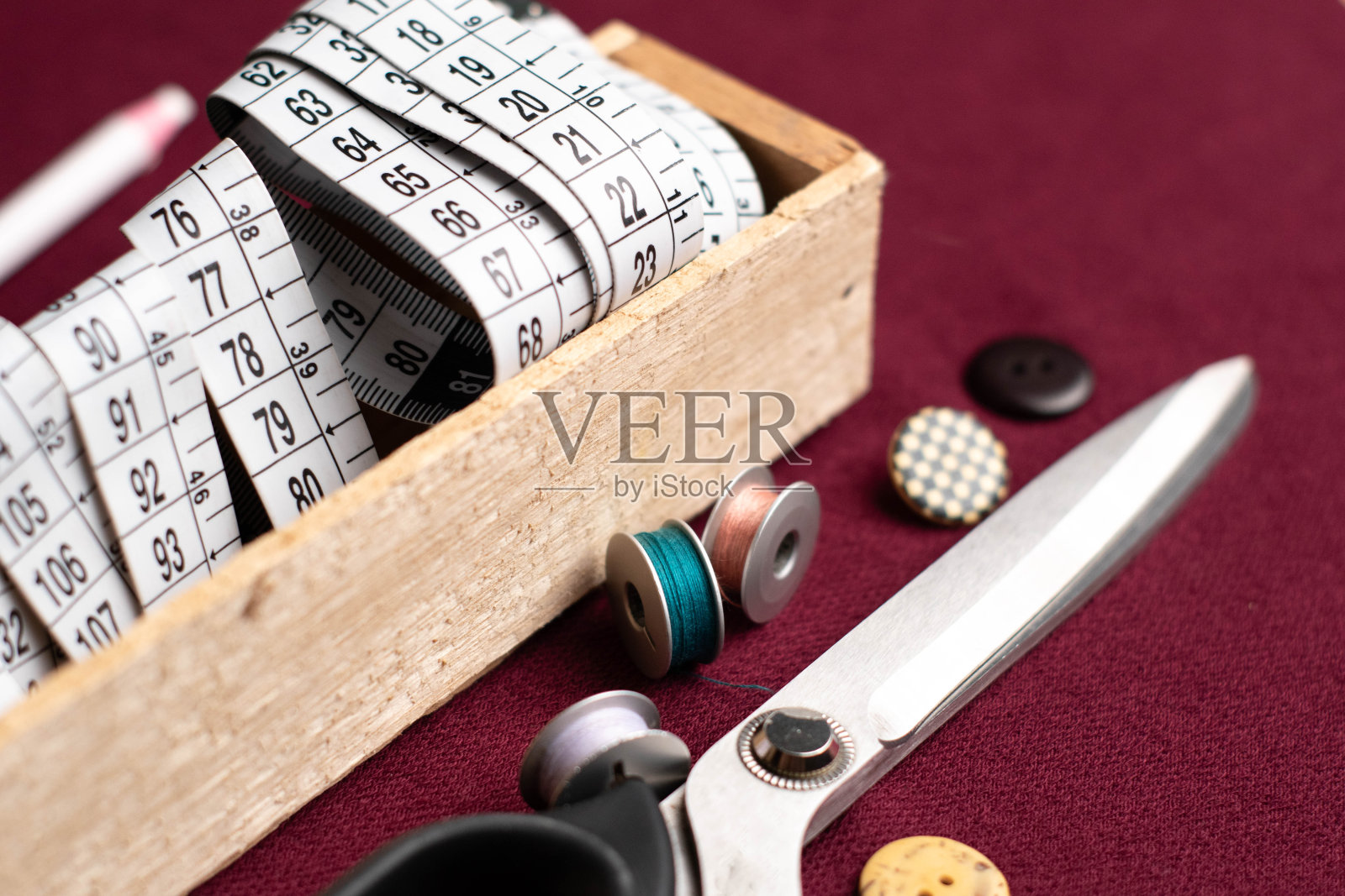 米装在木箱里，几卷线和金属剪刀放在暗红色的织物上照片摄影图片