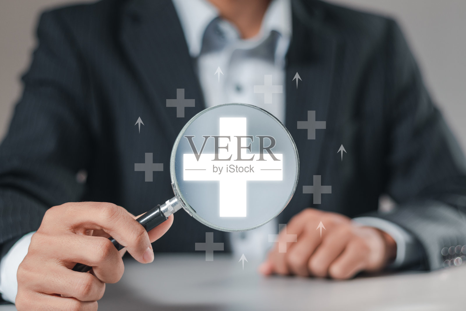 正的是加号的概念。商人用放大镜聚焦加符号为积极的事情，企业为利润、效益、健康保险、发展和成长。照片摄影图片