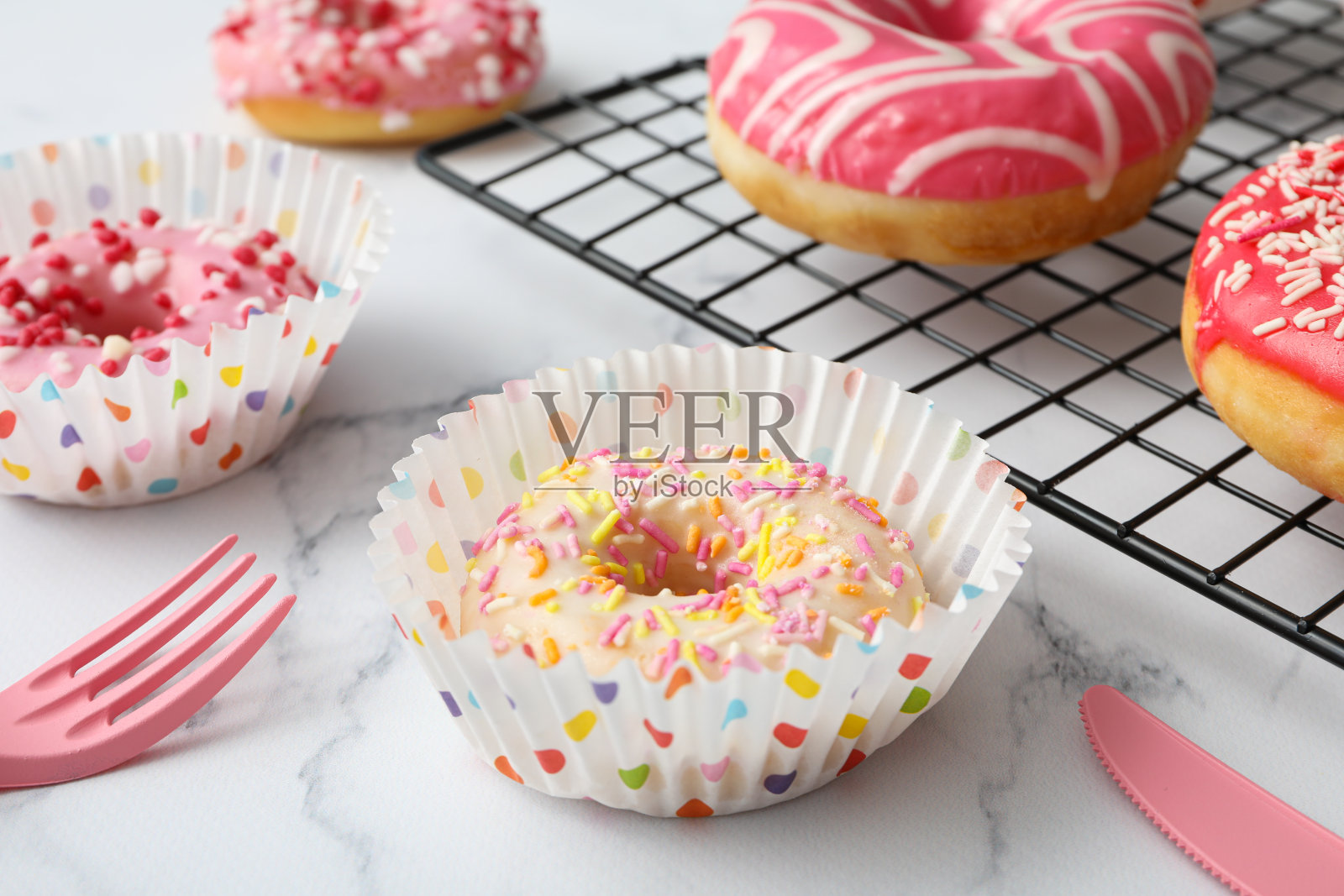 网格上的釉面甜甜圈和大理石背景上的纸杯蛋糕杯照片摄影图片