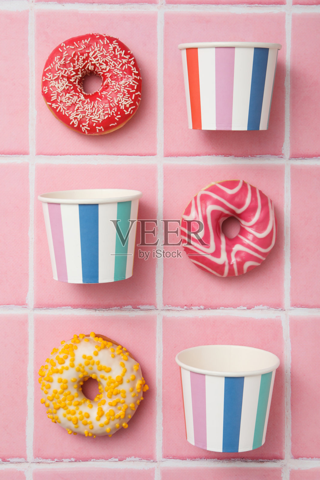 粉色瓷砖上的甜甜圈，还有纸杯照片摄影图片