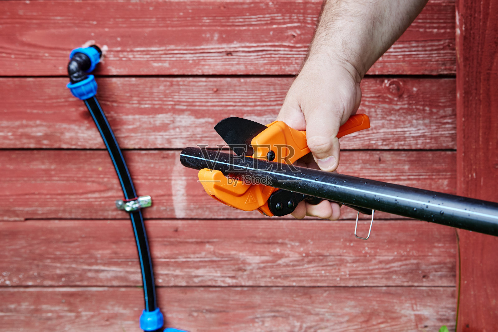 管道钳工在安装外部饮用水管道时，使用手刀切割HDPE管道。照片摄影图片