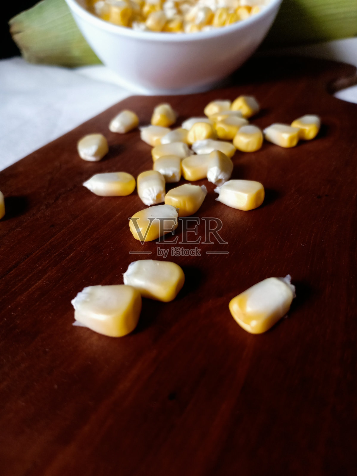 白色的桌子上放着剥了皮的玉米照片摄影图片