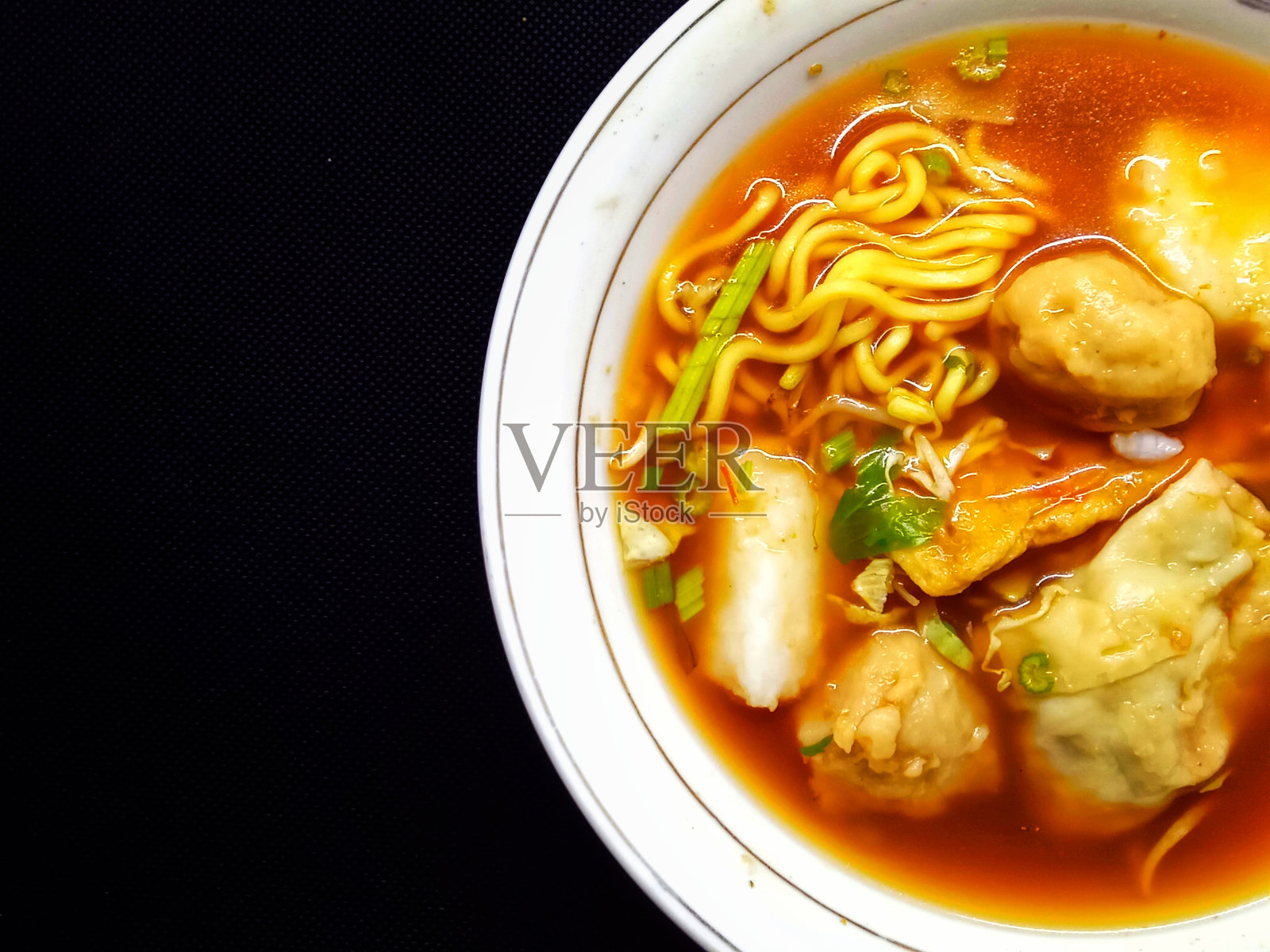 肉丸辣味汤，面条，黑背景炒豆腐的特写照片摄影图片