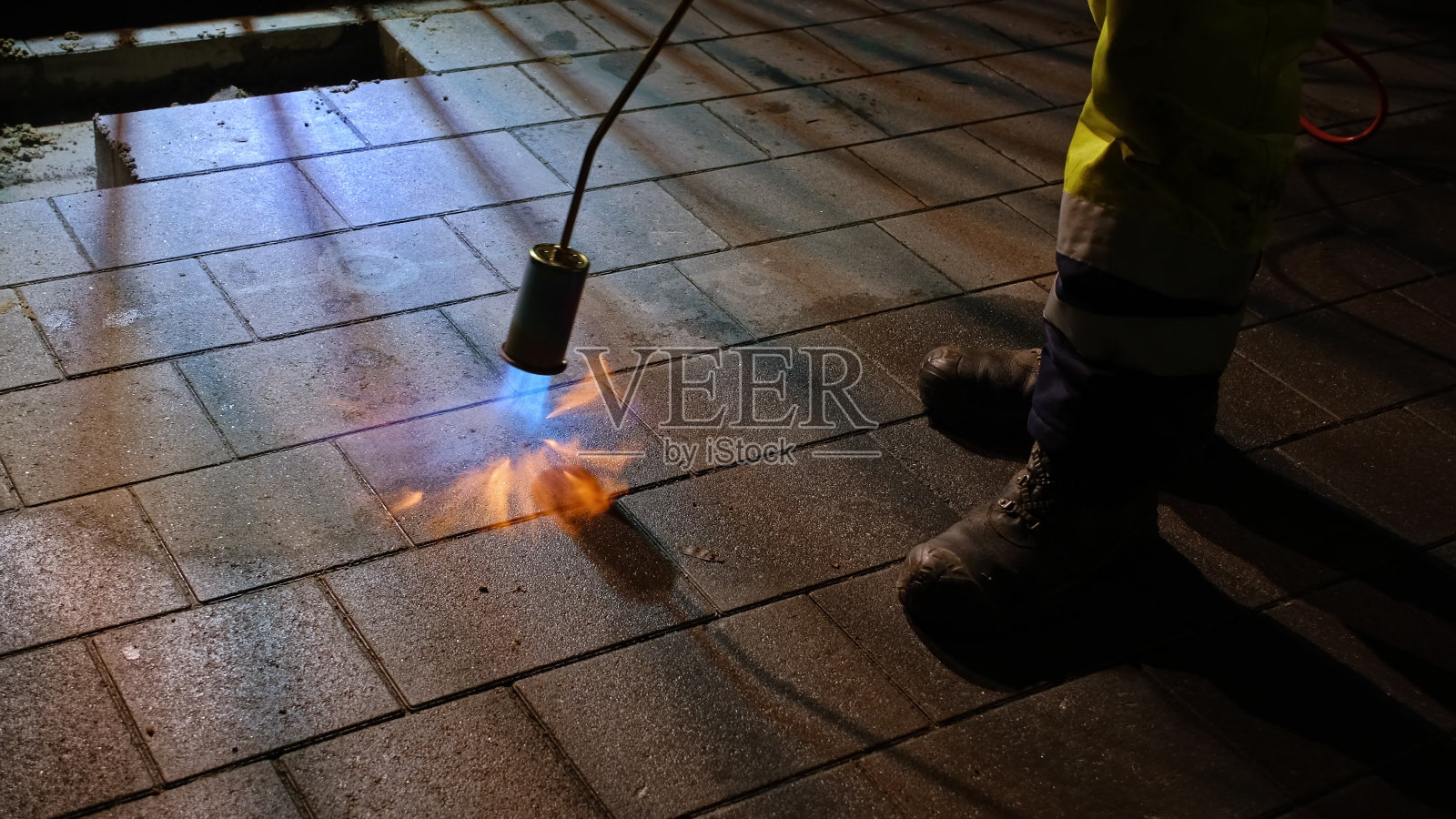 夜间道路施工工地工人用燃气火炬加热人行道石板照片摄影图片
