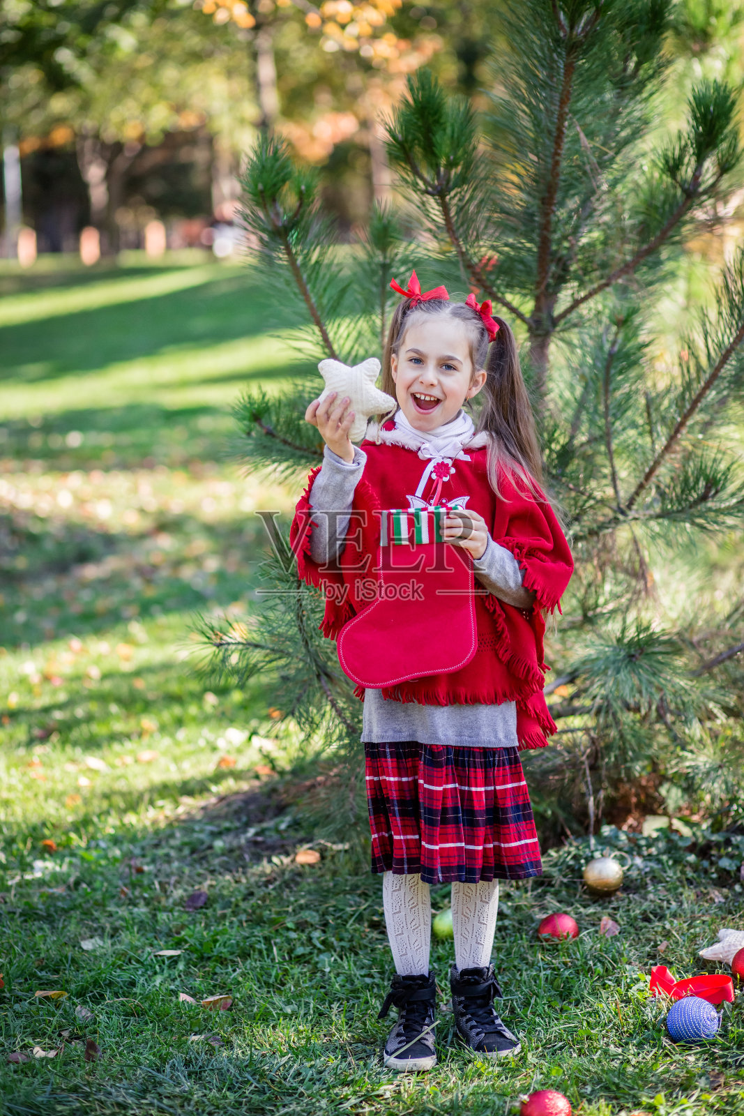 可爱的女孩在节日前在院子里装饰圣诞树。照片摄影图片