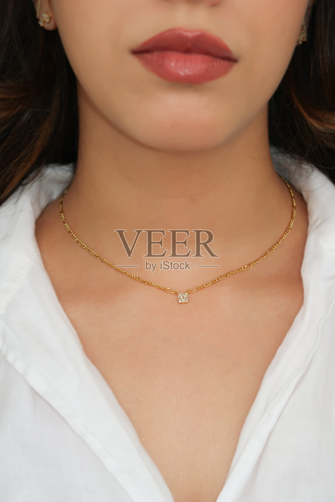 年轻女子戴着费加罗项链，项链上有方形锆石。照片摄影图片
