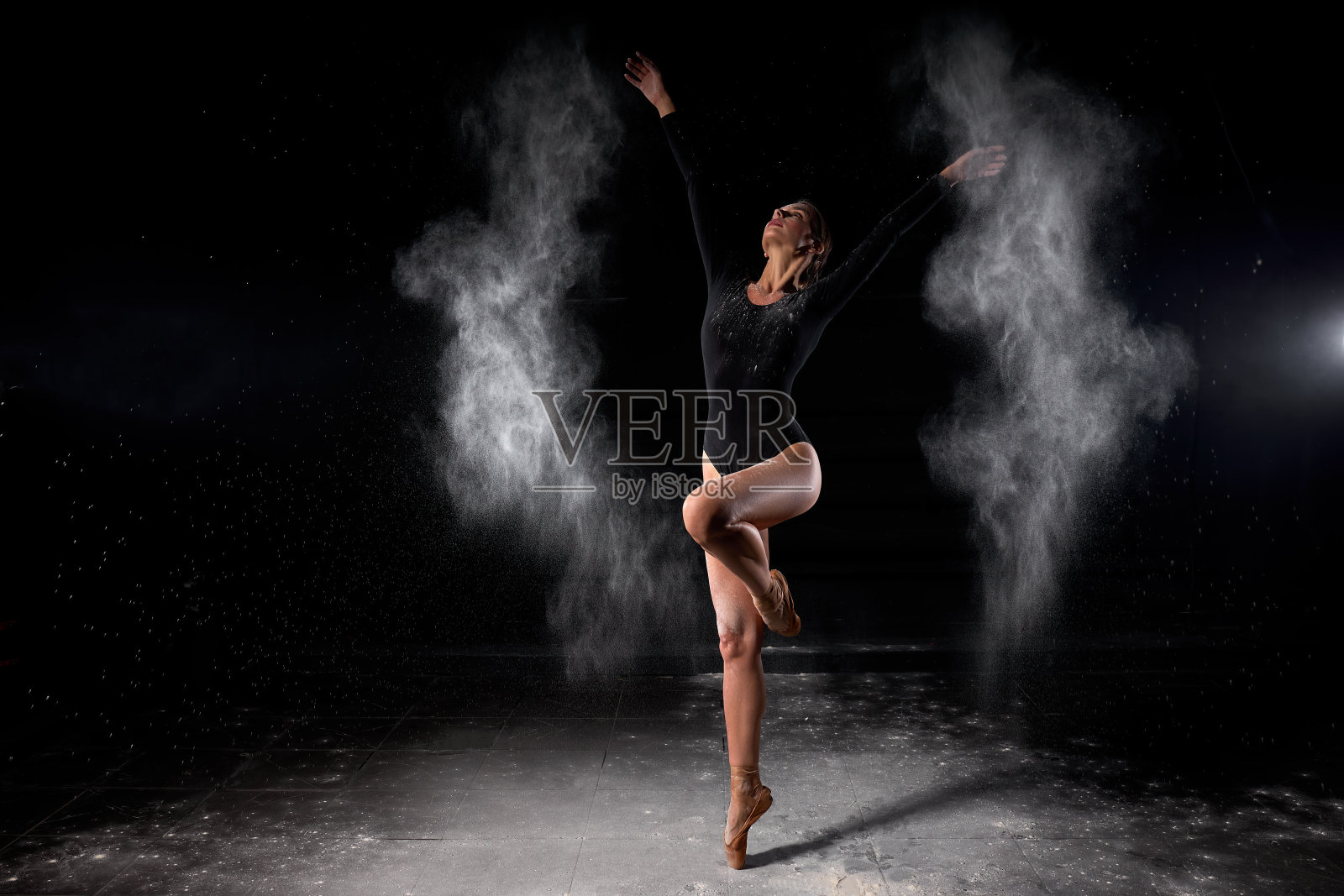 舞蹈家在舞蹈室里摆姿势，优雅地与灰尘、面粉一起跳舞。照片摄影图片