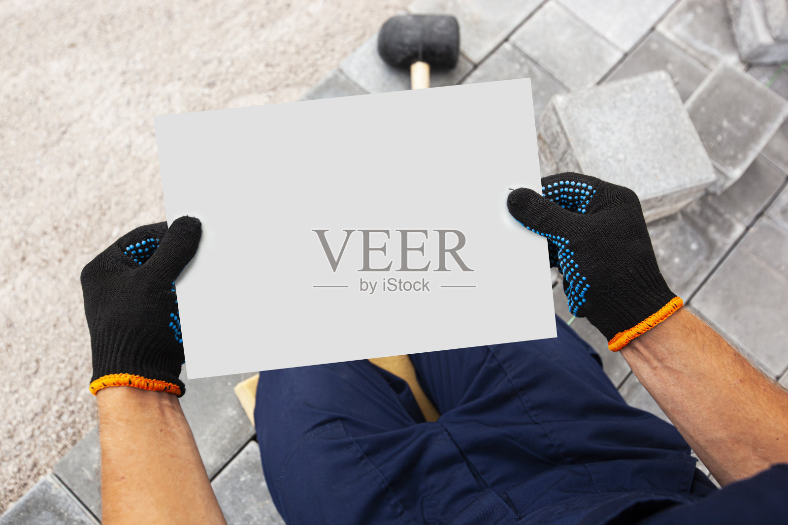 瓦匠戴着手套，手里拿着一张白纸。房屋维修或建筑的模型照片摄影图片