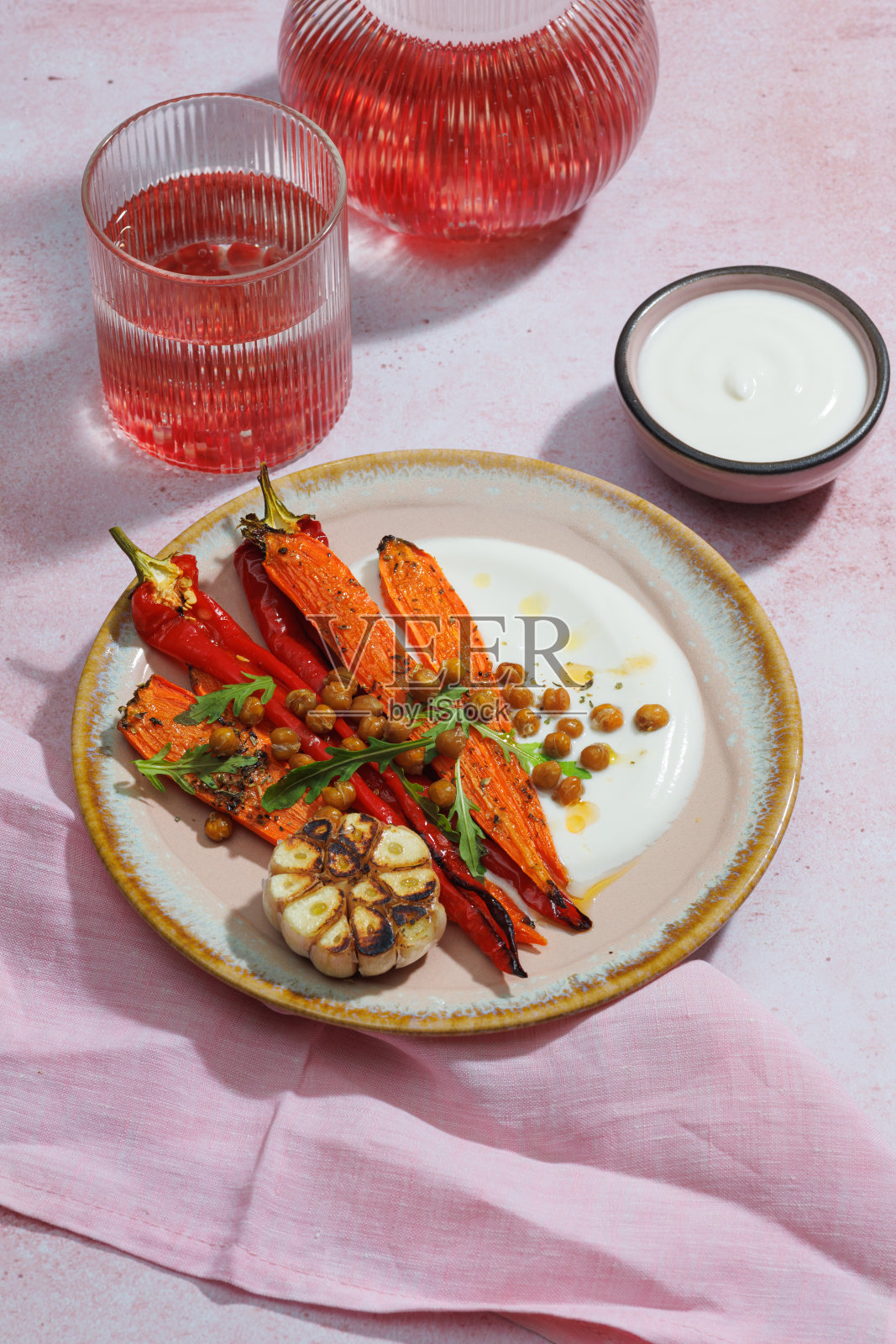 健康的自制烤胡萝卜即食与酸奶酱，素食主义者，素食主义者自制食物在粉红色的背景。垂直照片摄影图片