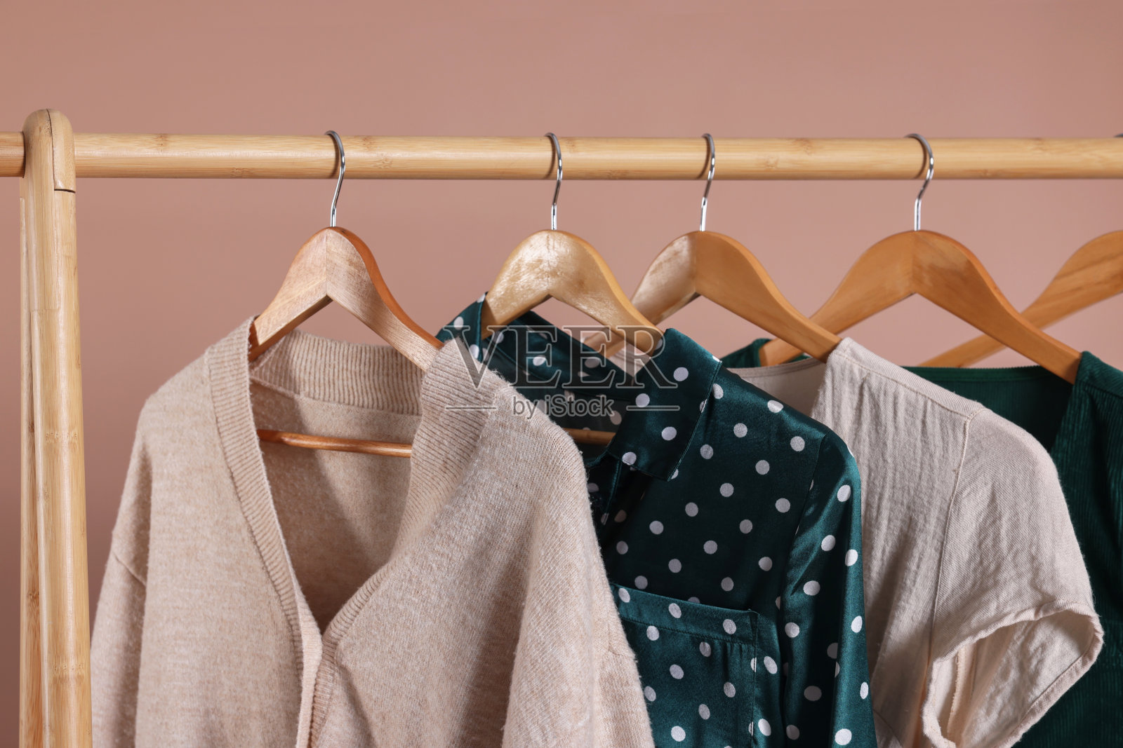 在米色背景下的木制衣架上有时尚女性服装的架子照片摄影图片