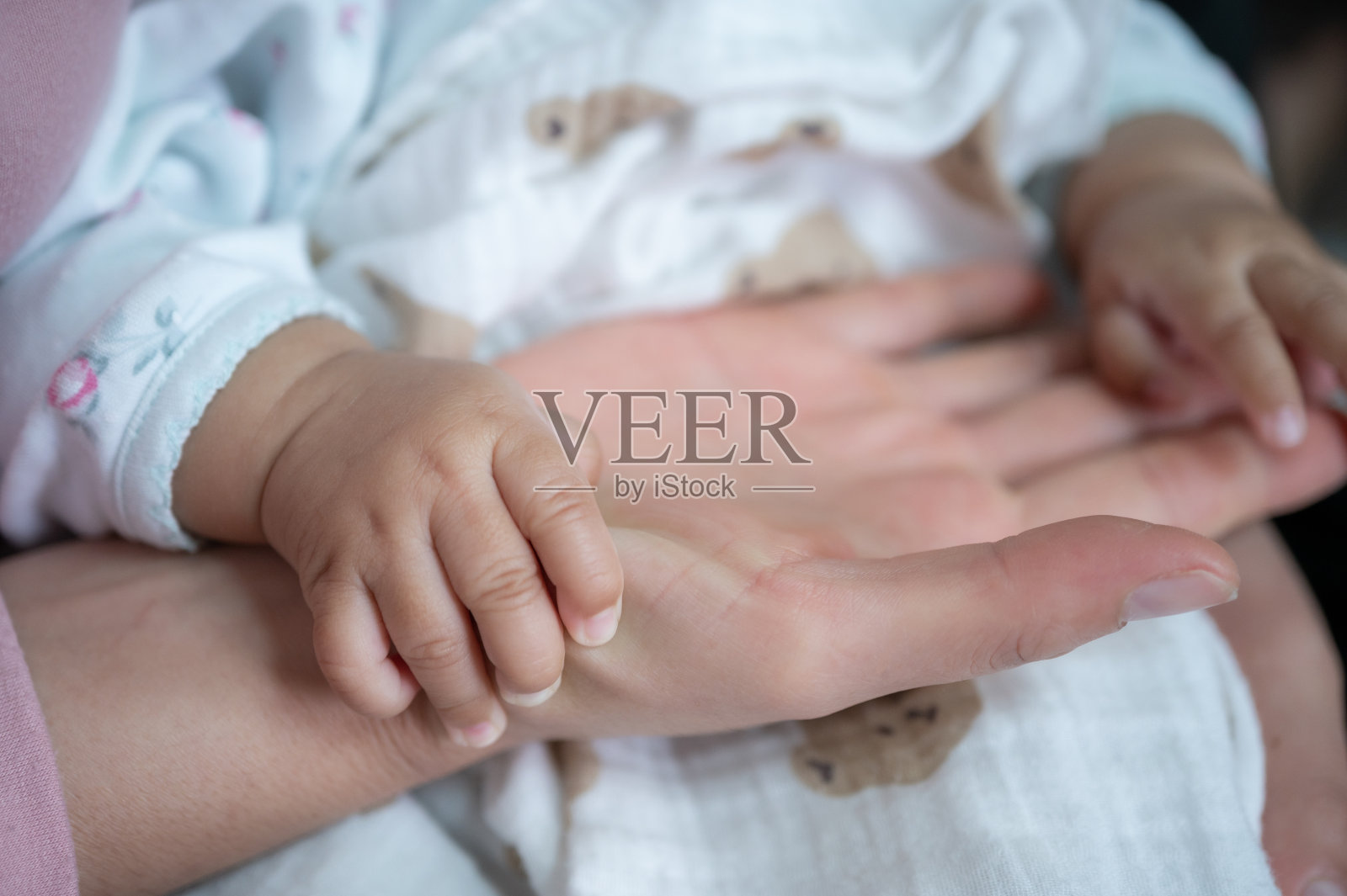 婴儿在睡觉时摸着父母的手。照片摄影图片