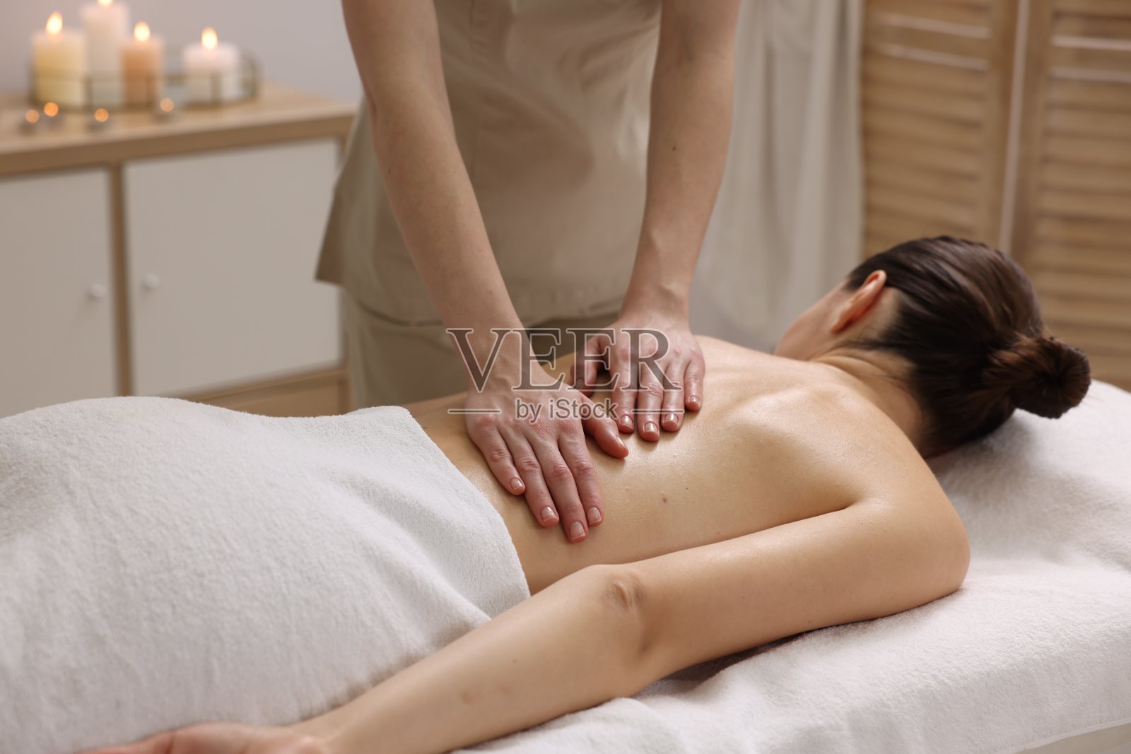 在水疗沙龙的沙发上接受背部按摩的女人照片摄影图片