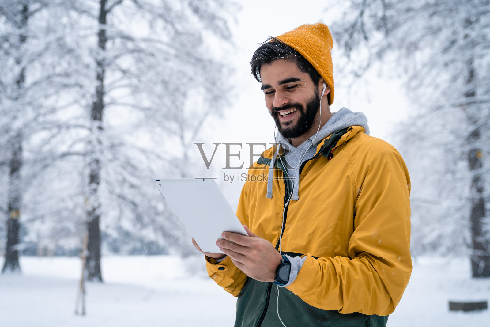 微笑的年轻自由职业者手里拿着平板电脑在冬天的风景照片摄影图片
