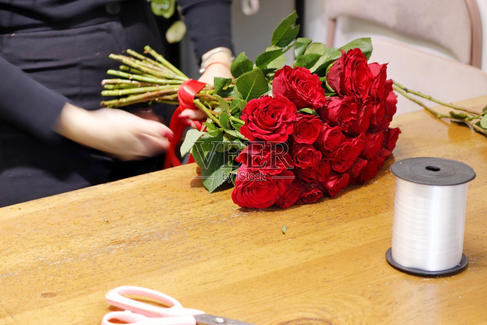 在花店里收集并装饰一束玫瑰。照片摄影图片