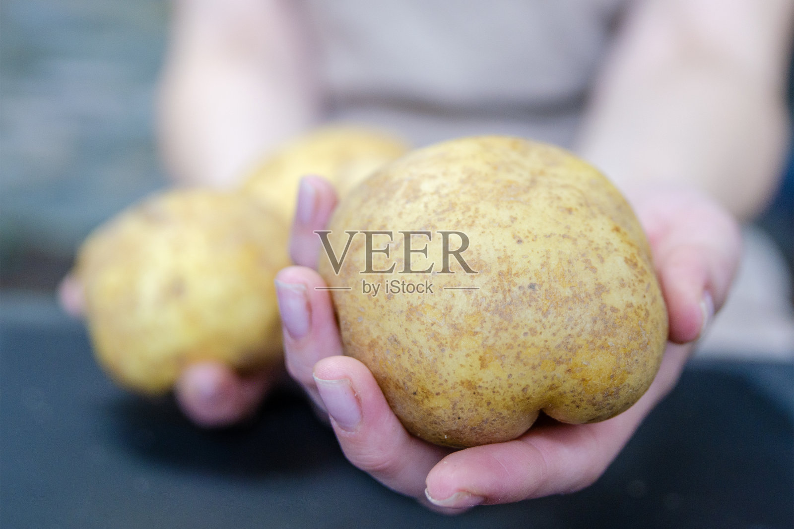 一只手拿着一个完整的未削皮的土豆特写。煮土豆或炸土豆。照片摄影图片