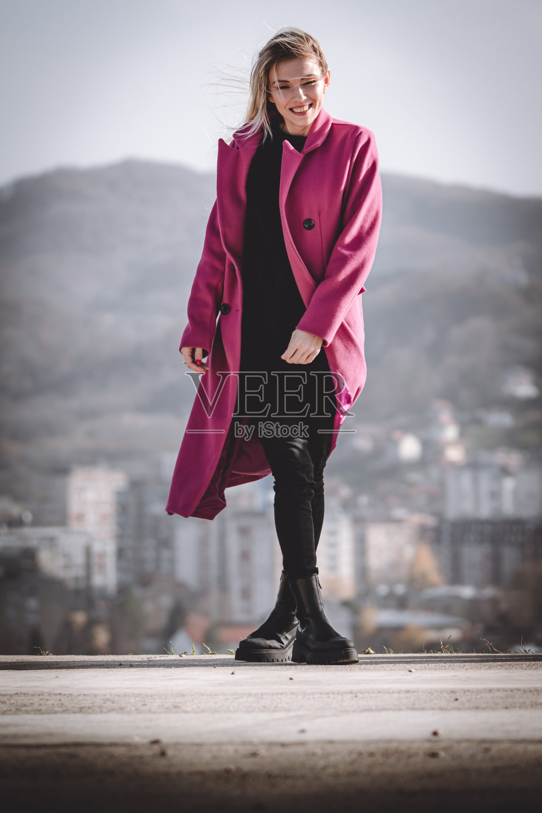 一个美丽的女人在刮风的日子里走在街上，头发飞扬照片摄影图片